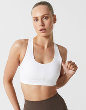 A model wearing a white sports bra and brown leggings