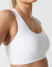 White sports bra worn by a person on a light gray background