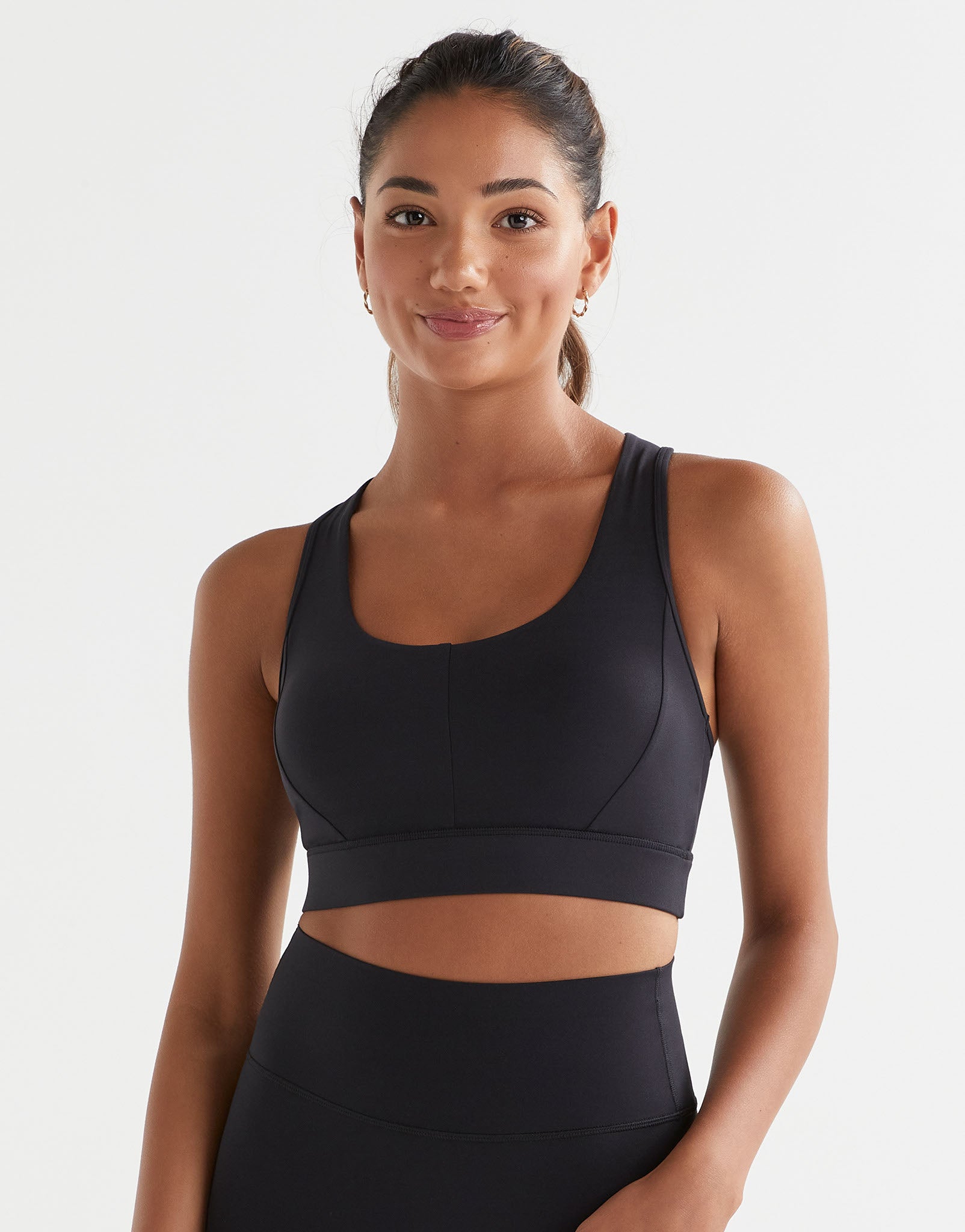 A woman wearing a black Lilybod Frankie Cloud-Core Sports Bra with wide straps and removable padded cups.