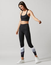 A model wearing black color-block leggings with white and gray accents, posing with a side view.