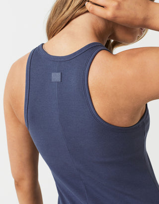 Person wearing a blue tank top with a visible brand logo on a light gray background
