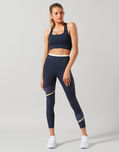A model wearing navy blue athletic outfit on a grey background