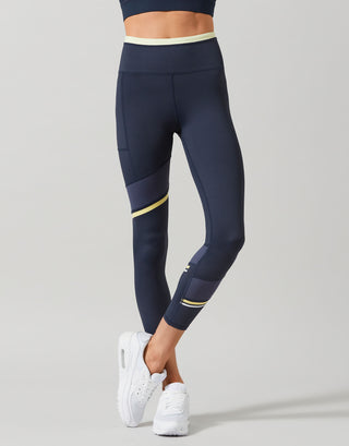 Navy leggings with yellow accents worn by a person on a gray background