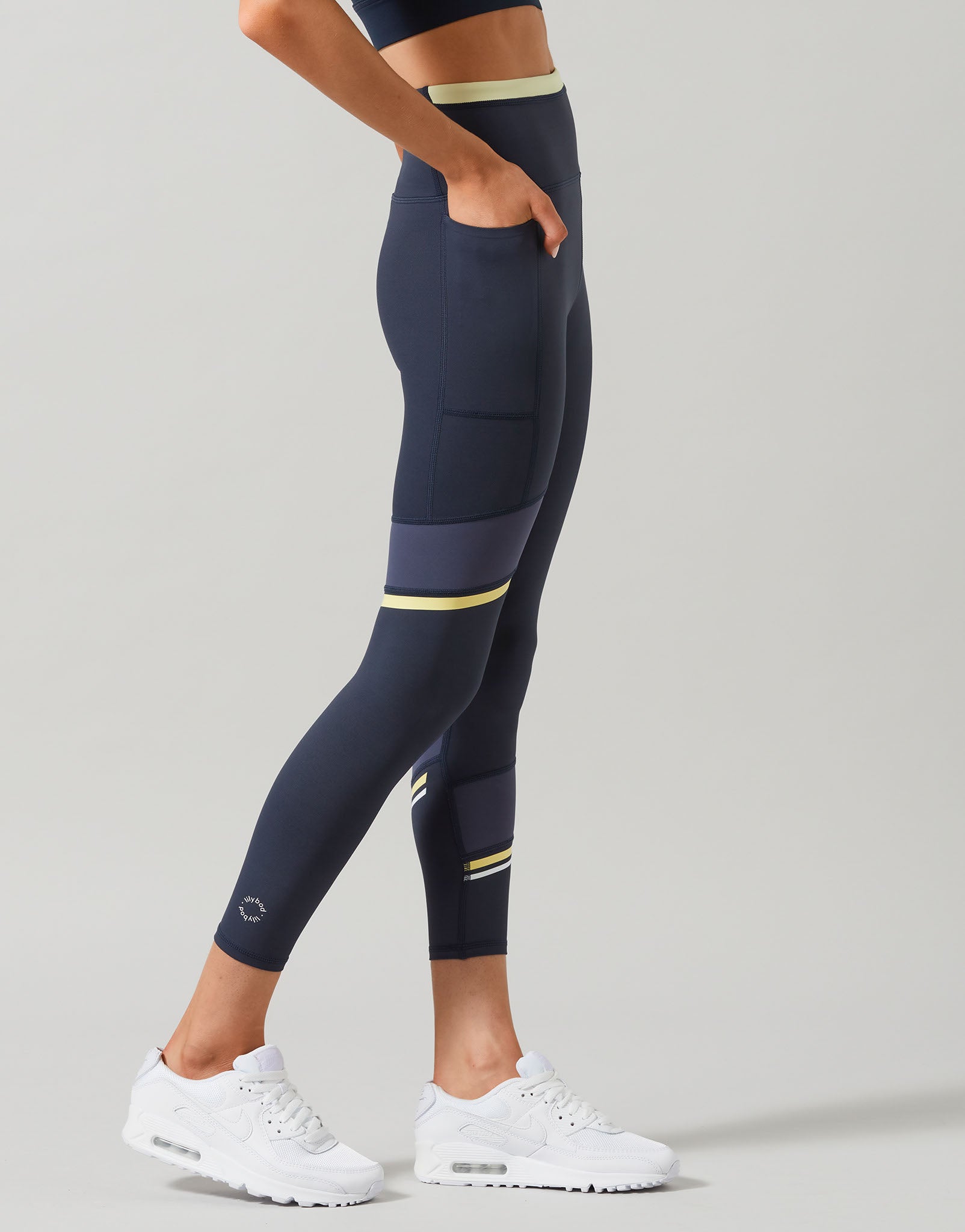 Person wearing navy leggings with yellow accents on a gray background