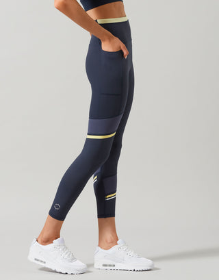 Person wearing navy leggings with yellow accents on a gray background