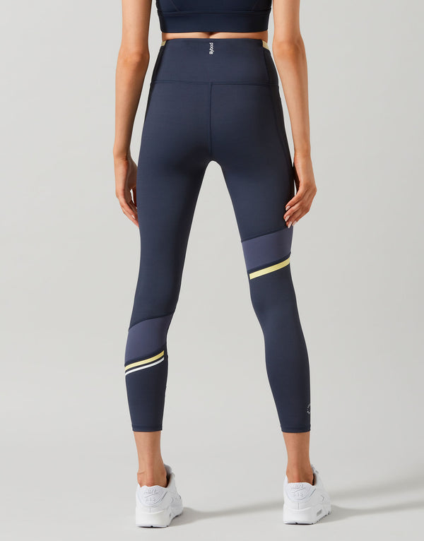 Woman wearing navy blue Lilybod leggings with a stripe on leg