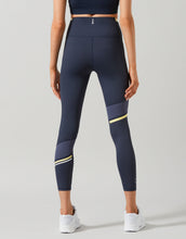 Woman wearing navy blue Lilybod leggings with a stripe on leg
