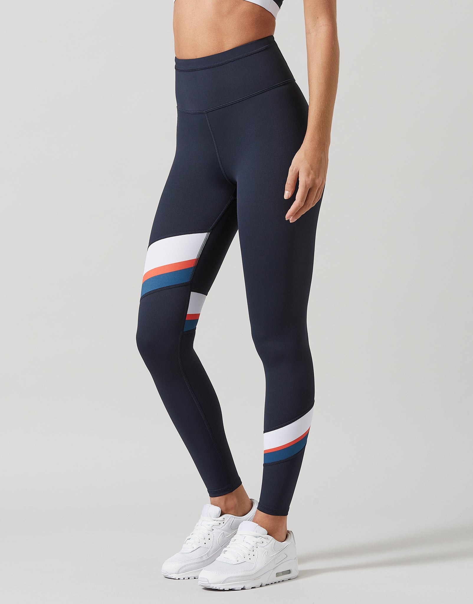Woman wearing navy blue leggings with a white and red stripe