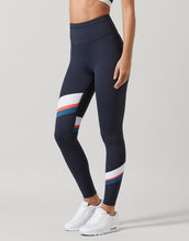 Woman wearing navy blue leggings with a white and red stripe