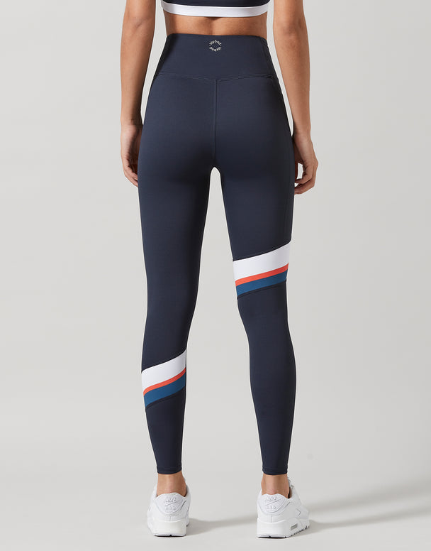 Woman wearing navy blue leggings with a white and red stripe