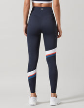Woman wearing navy blue leggings with a white and red stripe