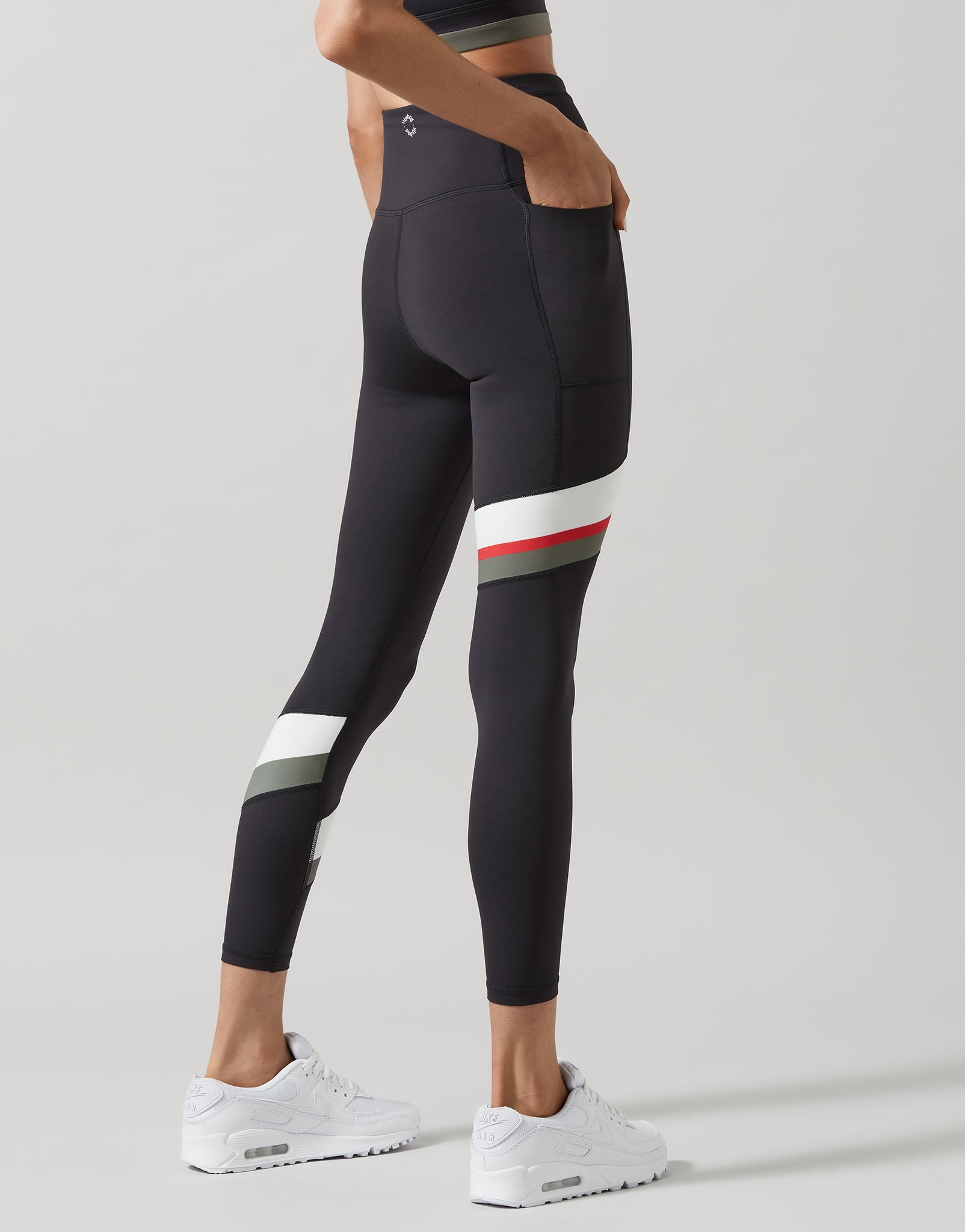 A model wearing dark grey leggings with stripes on a light grey background