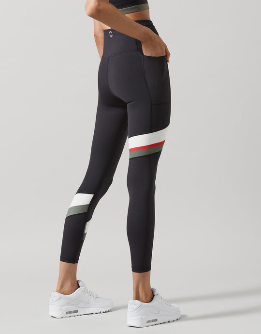 A model wearing dark grey leggings with stripes on a light grey background
