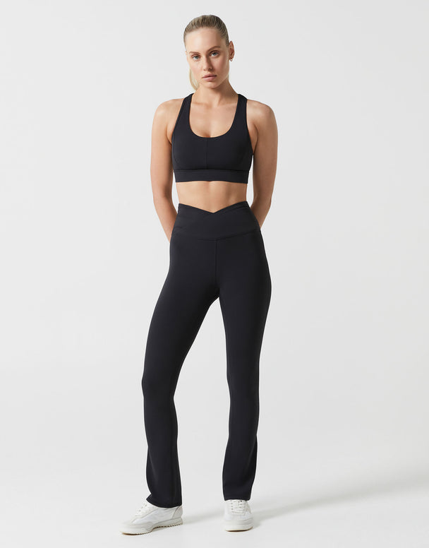 Woman wearing a black sports bra and leggings on a white background