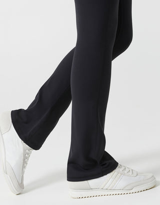 Black pants worn by a person with white sneakers on a light gray background
