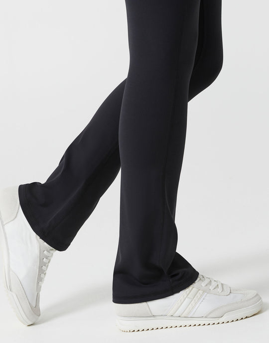 Black pants worn by a person with white sneakers on a light gray background