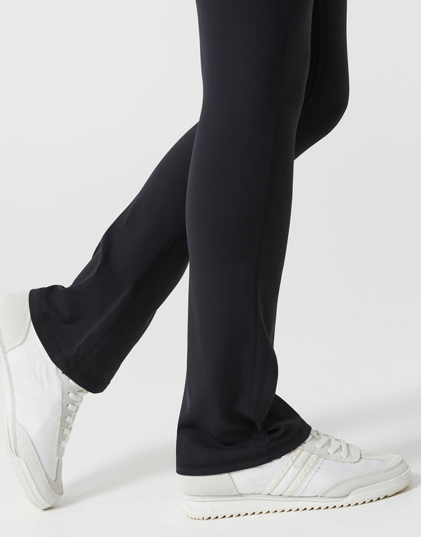 Black pants worn by a person with white sneakers on a light gray background