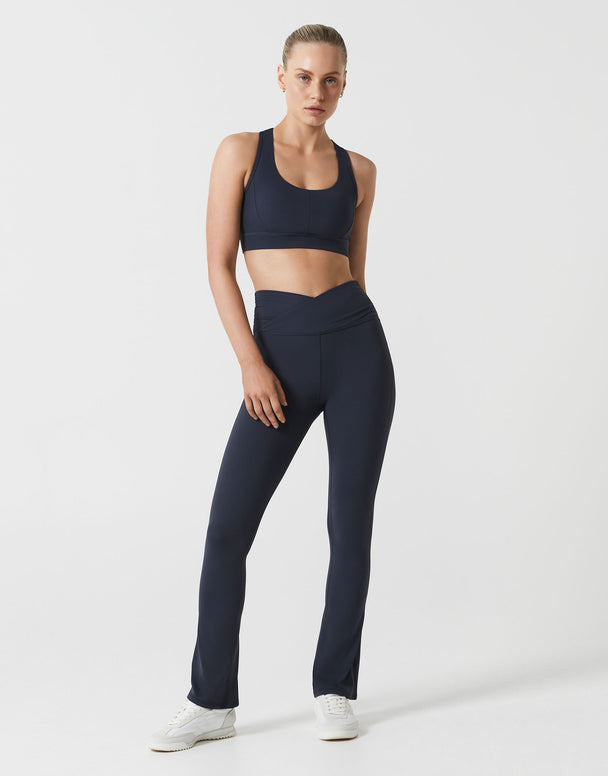 A woman wearing navy bootleg leggings and w matching top on a white background.