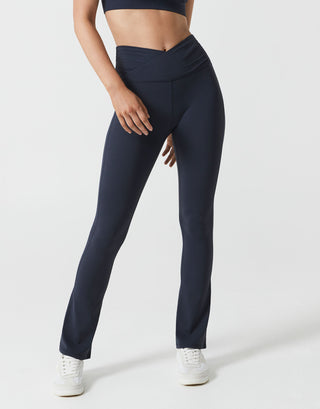 A woman wearing navy bootleg leggings on a white background.