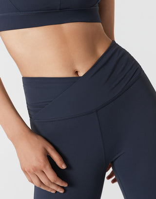 Close up of a woman wearing navy bootleg leggings on a white background.
