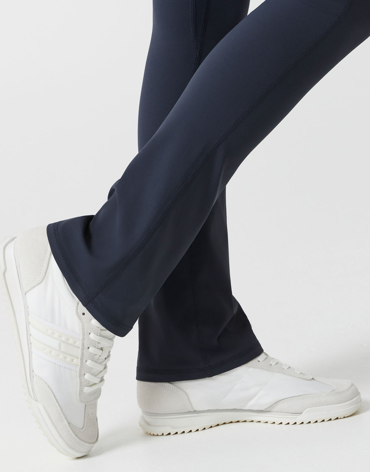 A woman wearing navy bootleg leggings on a white background close up.