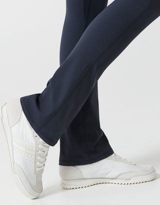 A woman wearing navy bootleg leggings on a white background close up.