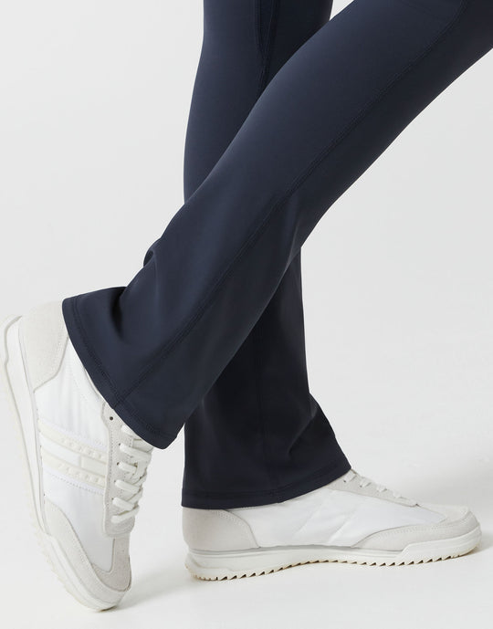 A woman wearing navy bootleg leggings on a white background close up.