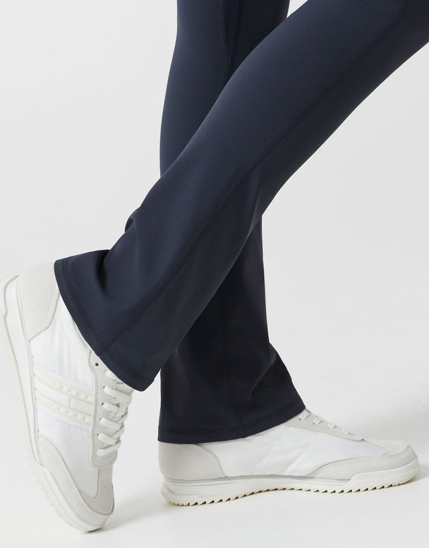 A woman wearing navy bootleg leggings on a white background close up.