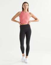 Woman wearing a pink top and black leggings on a white background