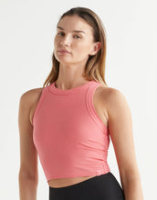 Woman wearing a pink ribbed tank top against a white background