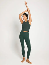 Woman in green athletic wear posing against a white background