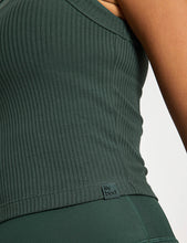 Green ribbed tank top with brand logo on a neutral background