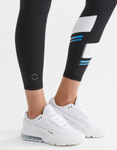 Black leggings with blue stripes worn by a person, paired with white sneakers on a light gray background