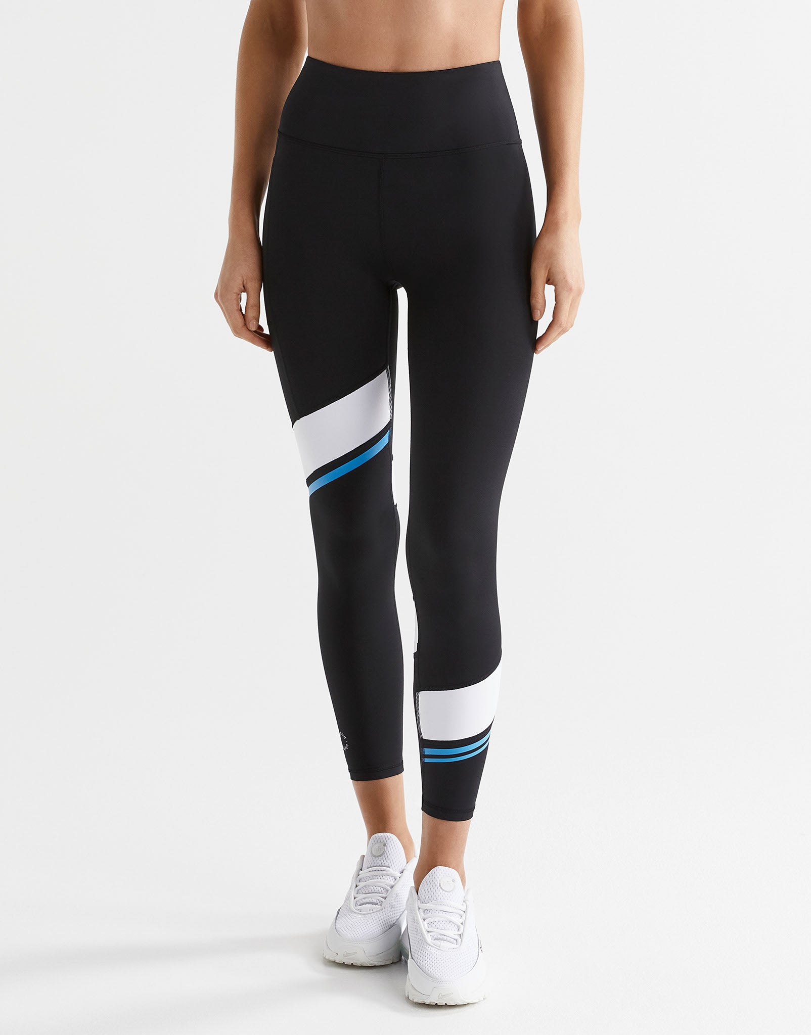 Person wearing black leggings with color block design on a white background