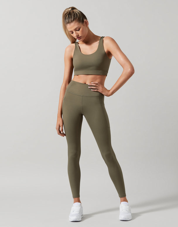 A model wearing high-waist full length khaki leggings with a Lilybod sports bra.