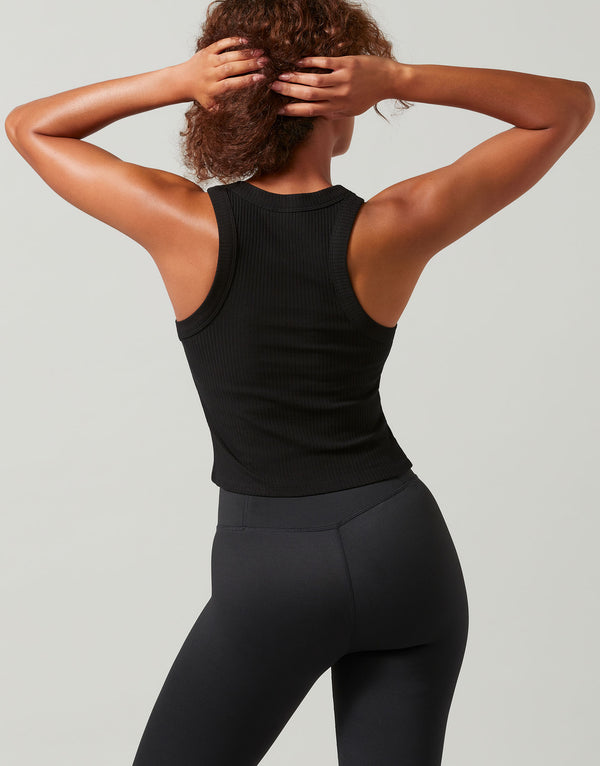 Person wearing a black tank top and leggings against a gray background