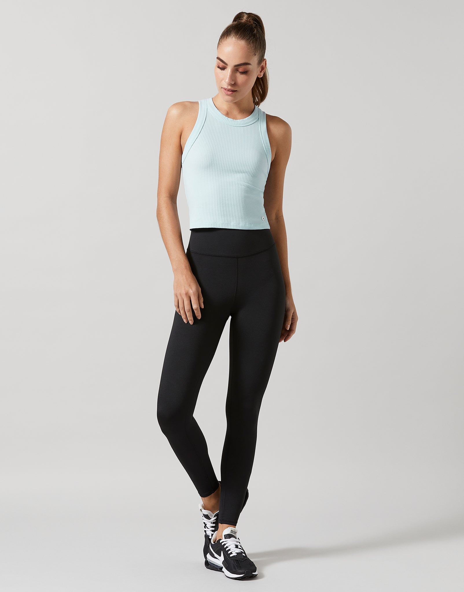 A model wearing a blue tank top and black leggings.