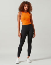 A woman wearing a bright orange tank white runners and black leggings