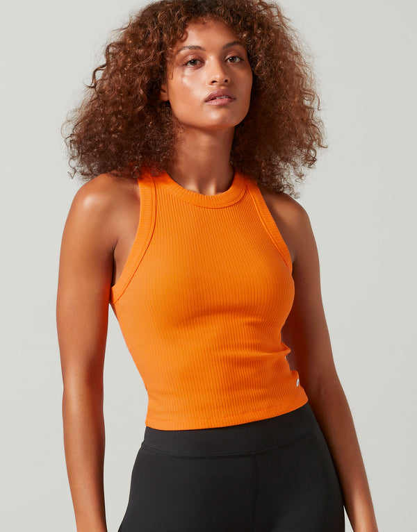 A woman wearing a bright orange tank and black leggings
