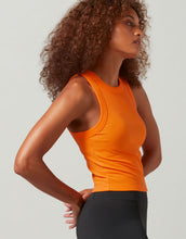 A woman wearing a bright orange tank  top and black leggings