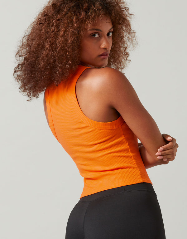 A woman wearing a bright orange ribbed tank and black leggings