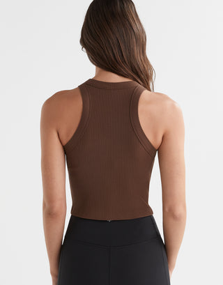 A  model wearing a brown Lilybod Harmony Tank Top in a slim-fit design, paired with black leggings.