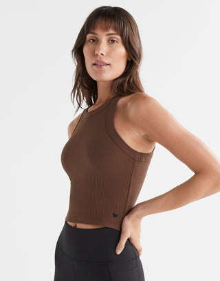 A woman wearing a brown Lilybod Harmony Tank Top in a slim-fit design, paired with black leggings.