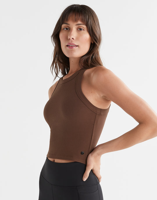A woman wearing a brown Lilybod Harmony Tank Top in a slim-fit design, paired with black leggings.