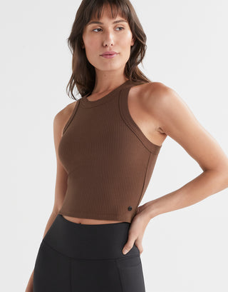 A female model wearing a brown  ribbed Lilybod Harmony Tank Top in a slim-fit design, paired with black leggings.