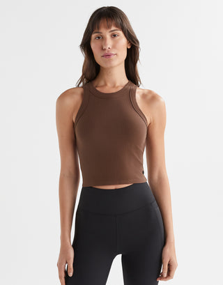 A female model wearing a brown Lilybod Harmony Tank Top in a slim-fit design, paired with black leggings.