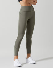Person wearing olive green leggings on a plain background