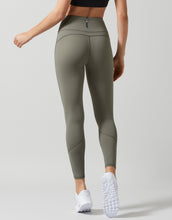 Person wearing olive green leggings on a light gray background