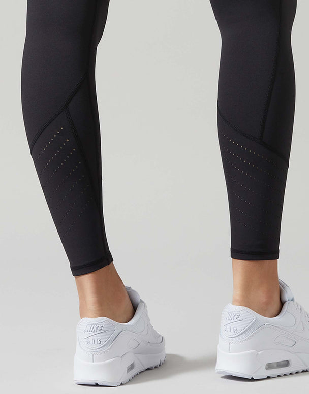 Black athletic leggings worn by a model, paired with white Nike Air Max sneakers, shown from the calves down against a light gray studio background.