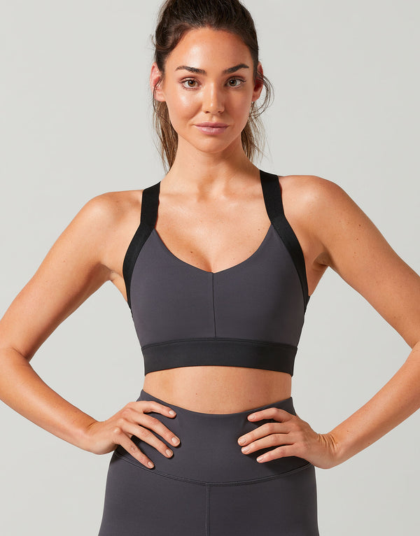 Woman wearing a black sports bra and leggings on a light gray background